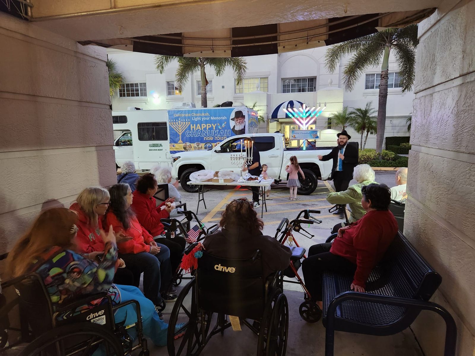 Menorah lighting ceremony under a covered patio at a senior facility